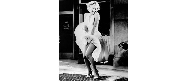 Which silver-screen icon is famously captured standing over a breezy subway grate in a brilliant white dress?
